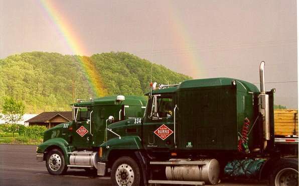 two Burns semi trucks and two rainbows in the sky behind them